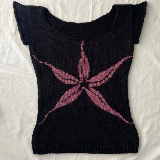 Knitted black baby tee with purple/pink intarsia flower design.