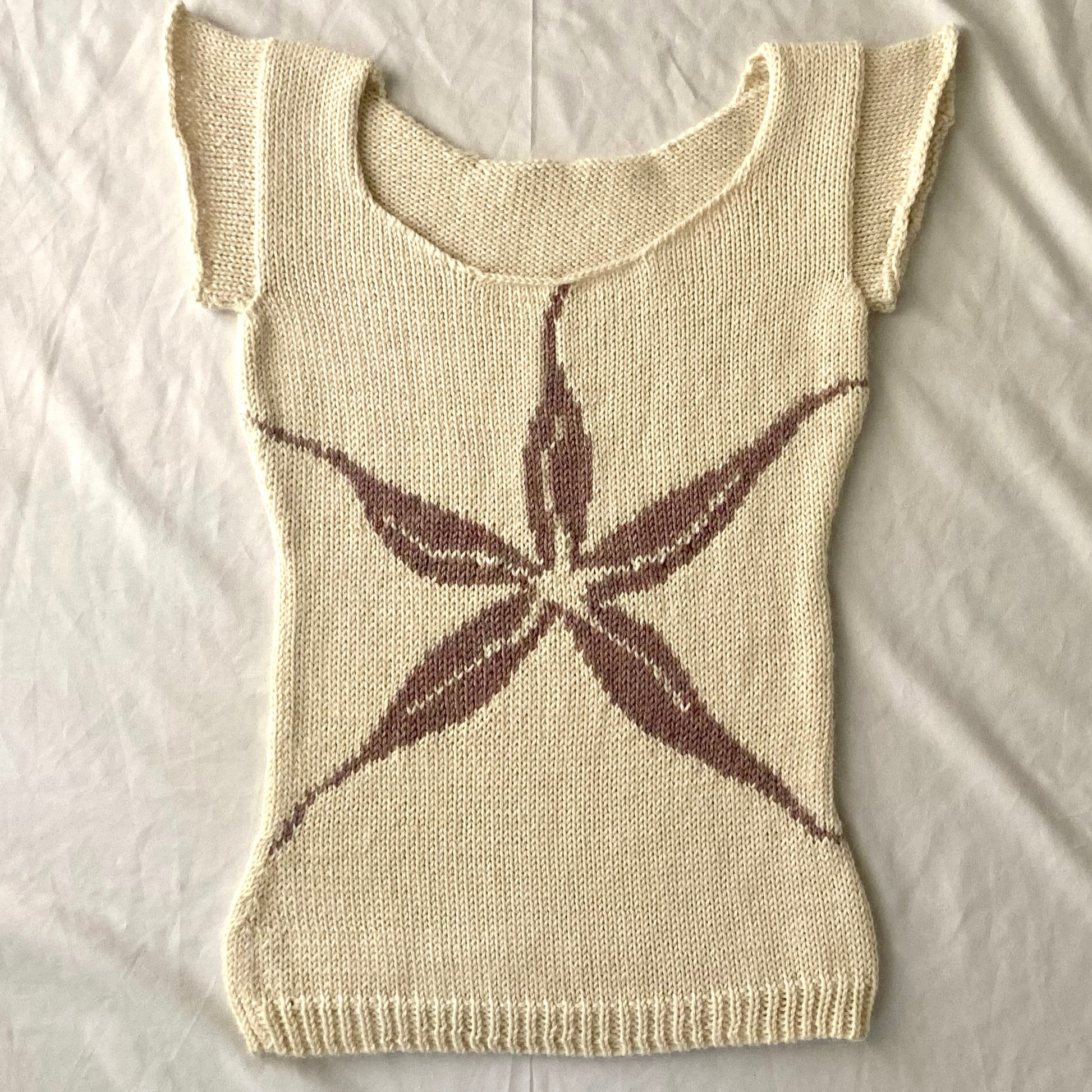 Knitted white baby tee with purple/pink intarsia flower design.